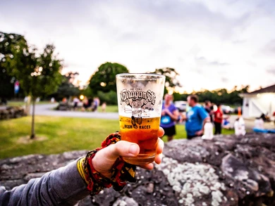 Runner holding a Summer Nights 5K branded beer glass filled with lager.